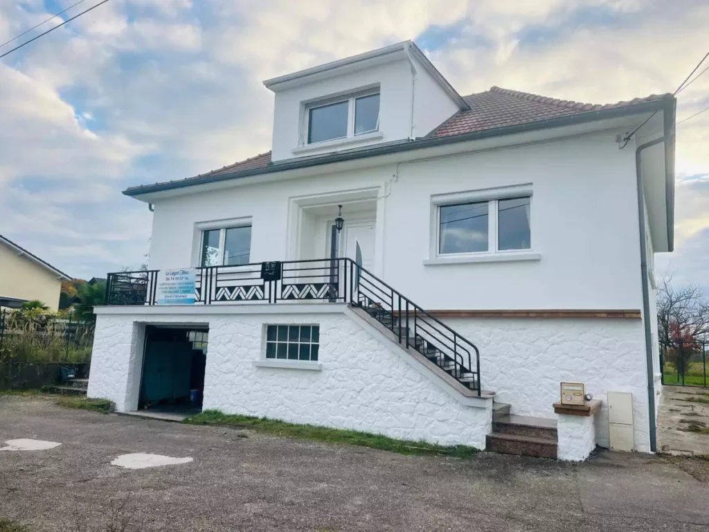 Maison rénovée avec façade blanche, toit gris et balcon noir à Créhange après ravalement de façade