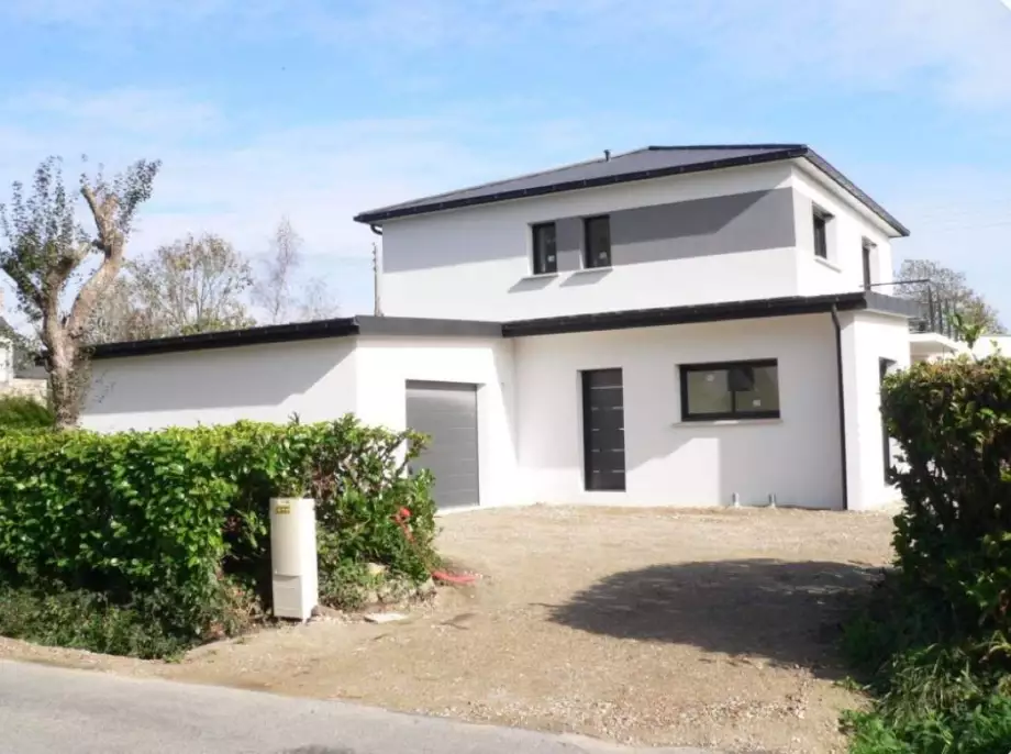 Maison moderne blanche deux étages avec garage, allée gravillonnée et haies vertes